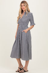 woman wearing a black and white gingham midi dress with short sleeves, button front, and pockets