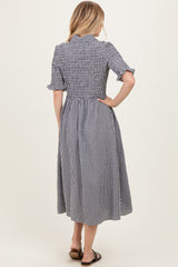 woman wearing a black and white gingham midi dress with short sleeves and a smocked bodice, seen from the back