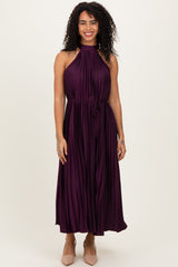 woman wearing a sleeveless dark purple pleated maxi dress with a halter neck and drawstring waist