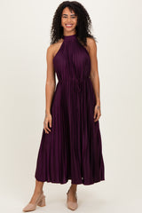 woman wearing a sleeveless deep purple pleated maxi dress with a halter neck and tie waist detail