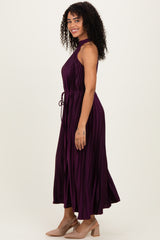 woman wearing a purple halter neck maxi dress with pleated design and a tie waist detail