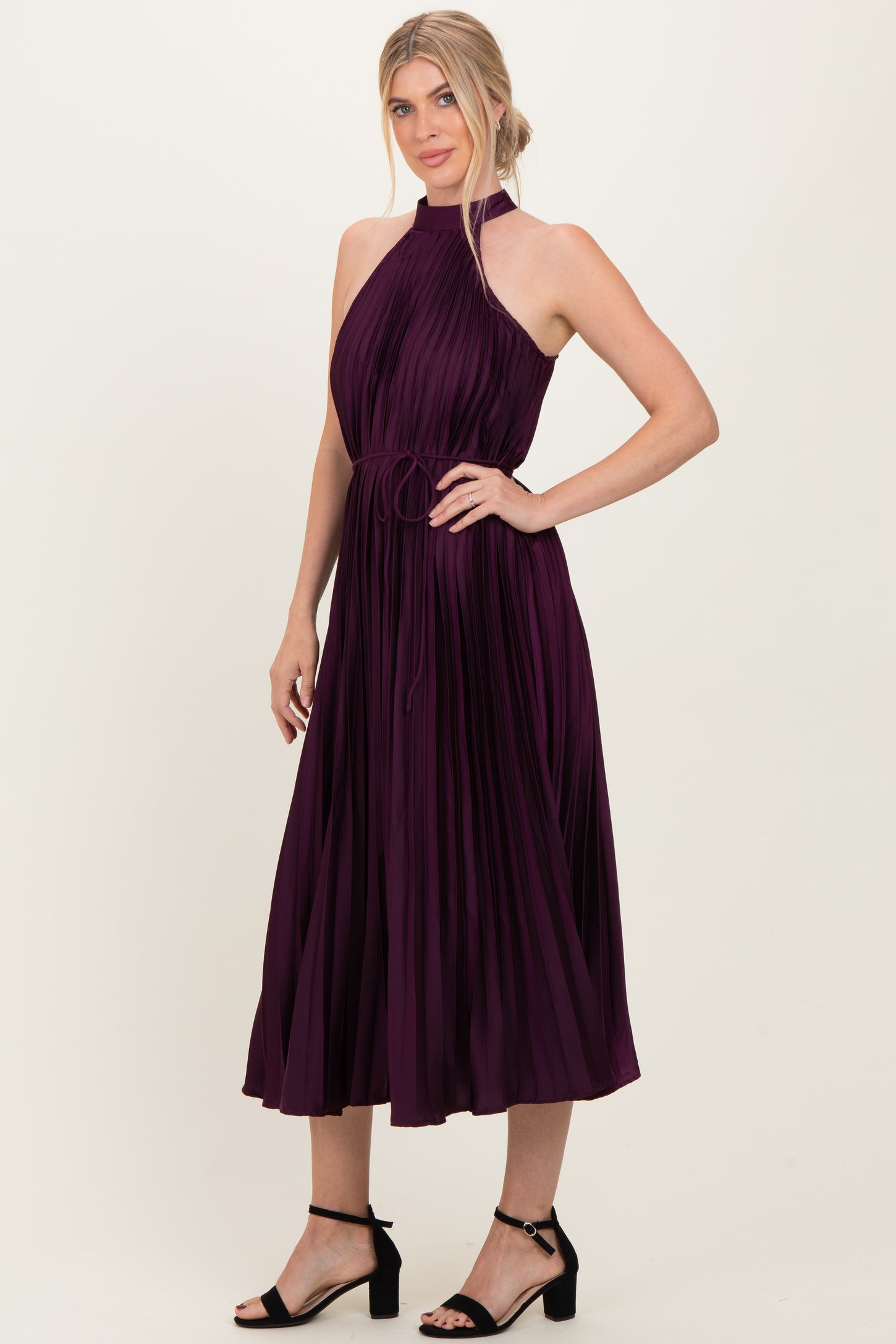 woman wearing a plum pleated midi dress with a halter neckline and tie waist detail