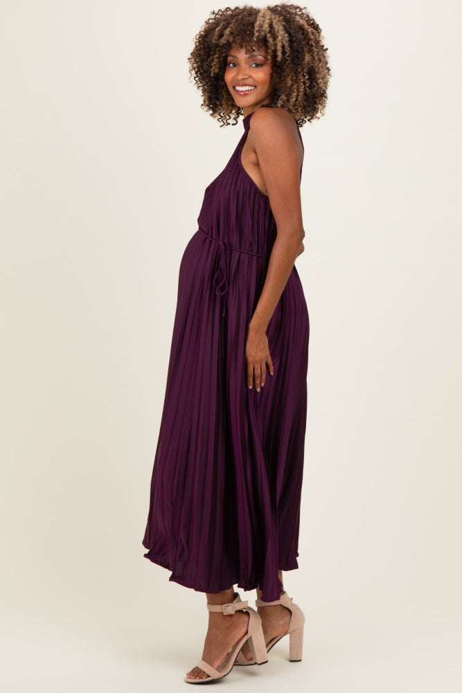 woman wearing a purple pleated maternity dress, showcasing her baby bump, paired with high-heeled sandals