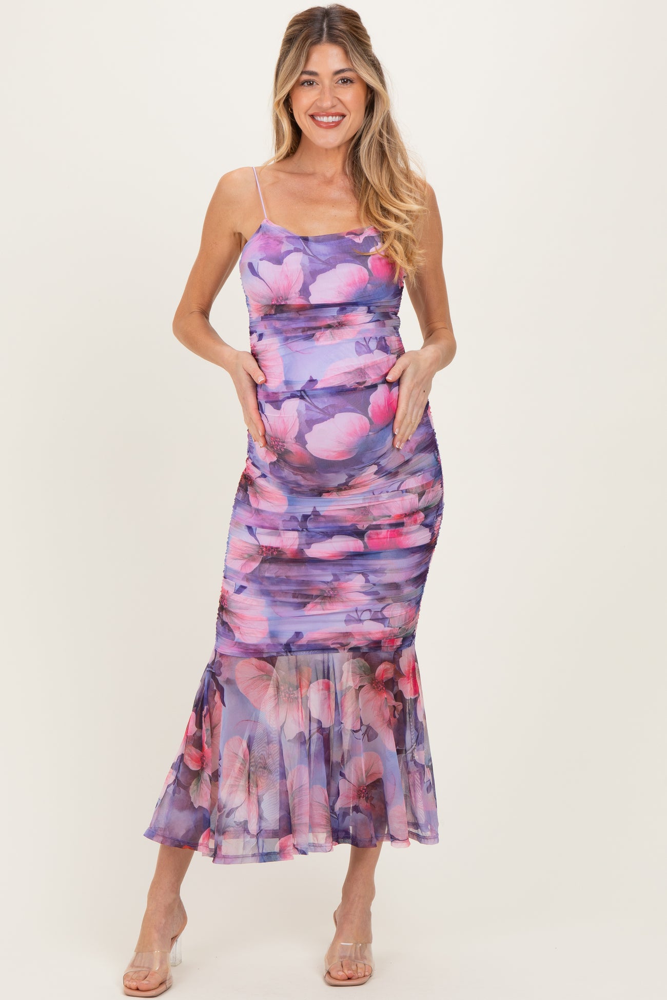 woman wearing a purple floral print maternity dress with a fitted bodice and flared hem, showing her baby bump