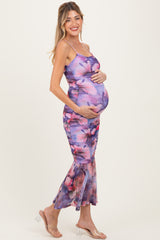 woman wearing a purple floral maternity dress with a fitted bodice and flared hem, showcasing her baby bump