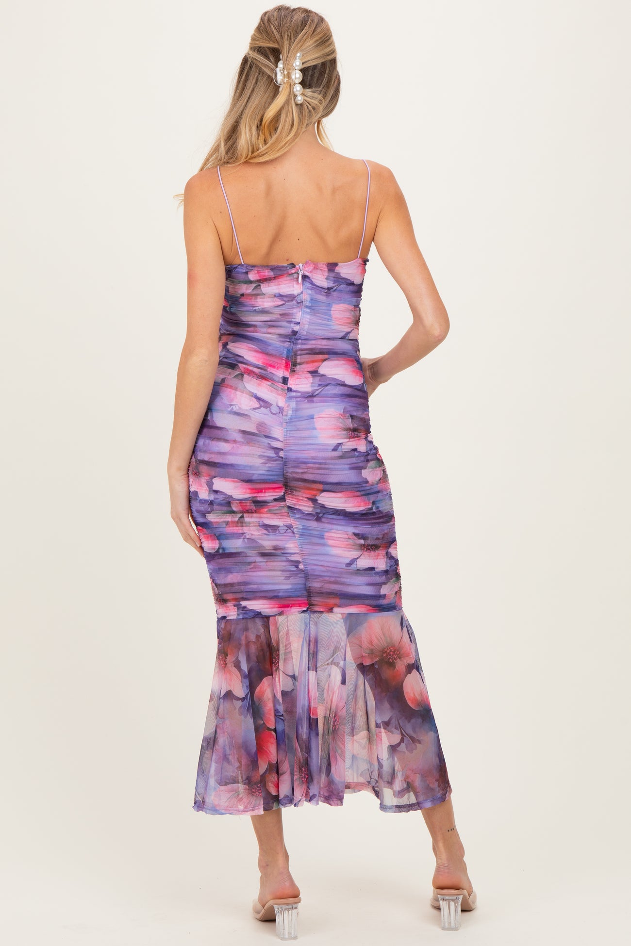 woman wearing a purple floral maternity dress with a fitted bodice and flared hem, showing her baby bump from the back