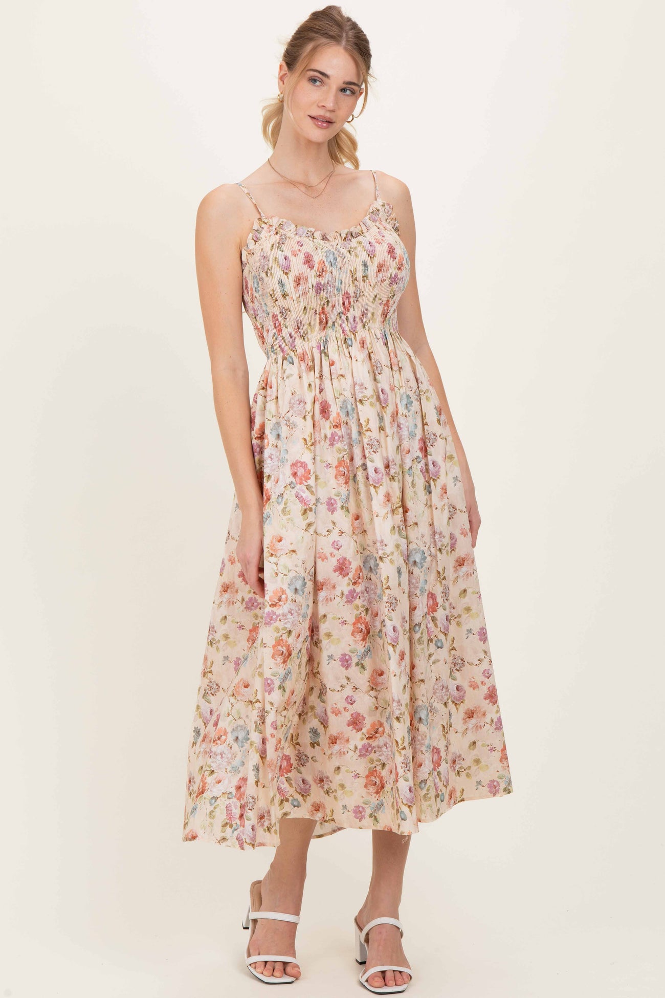 woman wearing a floral maxi dress with thin straps and a smocked bodice in pastel colors