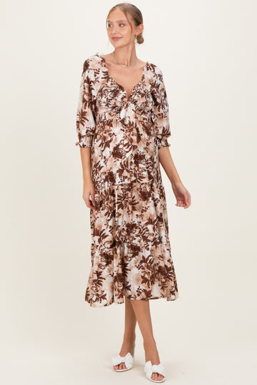 woman wearing a brown floral print maternity dress with a tie front and elbow-length sleeves, showing her baby bump