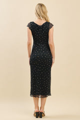 woman wearing a black midi dress with floral print and sheer cap sleeves, viewed from the back