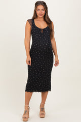 woman wearing a black floral maternity dress with a tie front, showcasing her baby bump and styled with nude heels