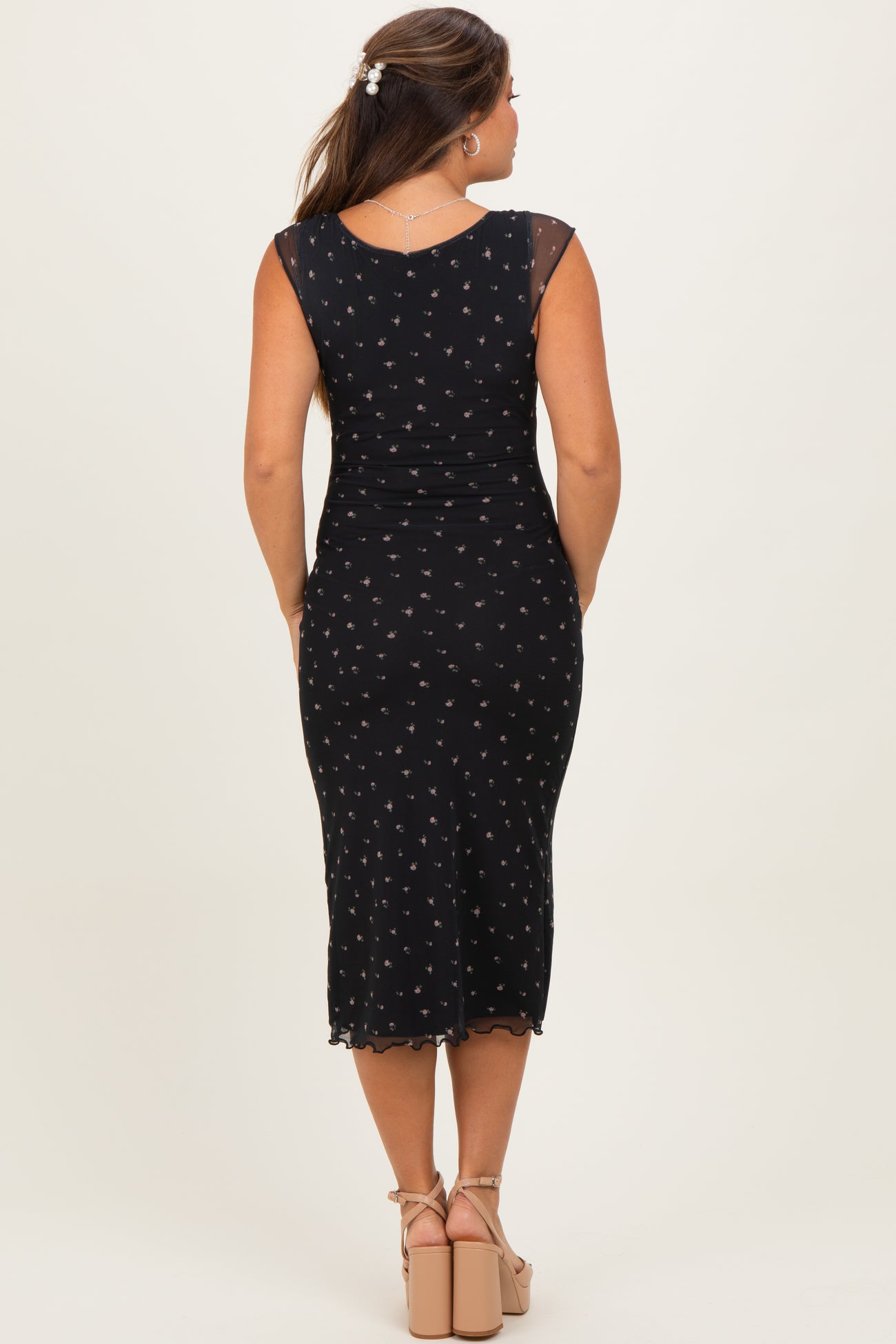 woman wearing a black maternity dress with floral print and a fitted silhouette, seen from the back