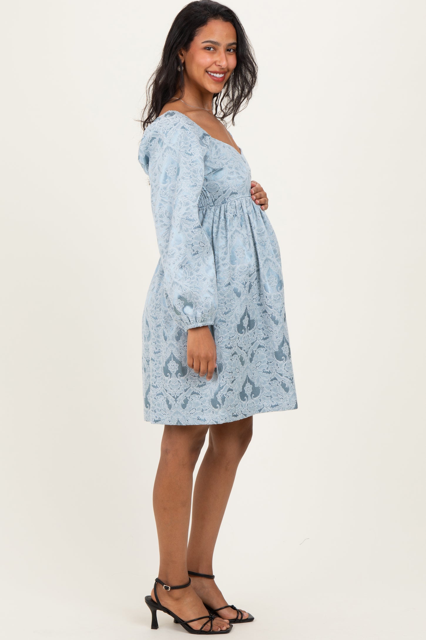 woman wearing a light blue floral maternity dress with a square neckline and puff sleeves, showcasing her baby bump
