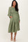 woman wearing a dark green long sleeve maternity dress with a flared skirt and pockets, showing her baby bump
