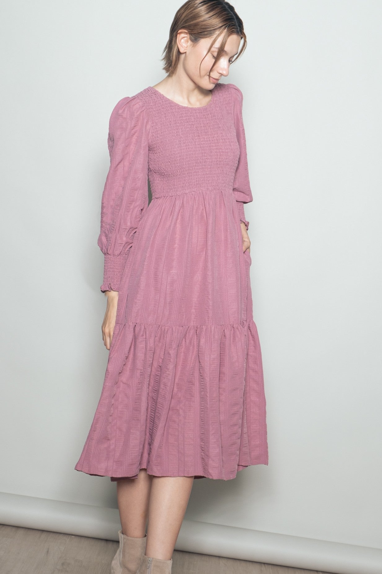 woman wearing a pink long sleeve smocked dress with a tiered skirt and puff sleeves