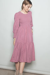 woman wearing a pink long sleeve smocked dress with a tiered skirt and puff sleeves