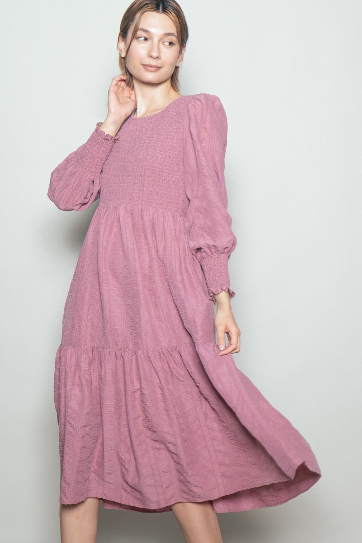 woman wearing a dusty pink long sleeve tiered maxi dress with smocked bodice and puff sleeves