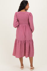 woman wearing a pink maternity dress with smocked bodice and tiered skirt, showing the back view