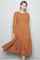 woman wearing a rust-colored long sleeve smocked midi dress with a tiered skirt and flowing fit