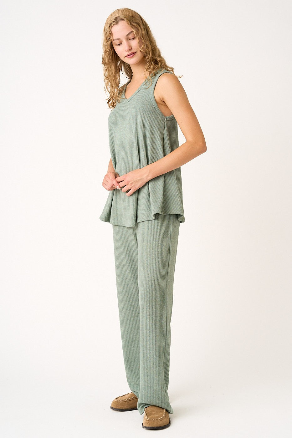 woman wearing a green ribbed peplum tank top and matching wide-leg pants, styled casually with slip-on shoes