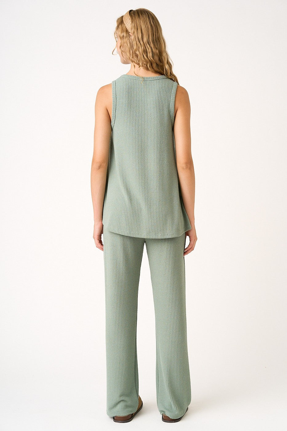 woman wearing a light green sleeveless top and matching wide-leg pants, viewed from the back