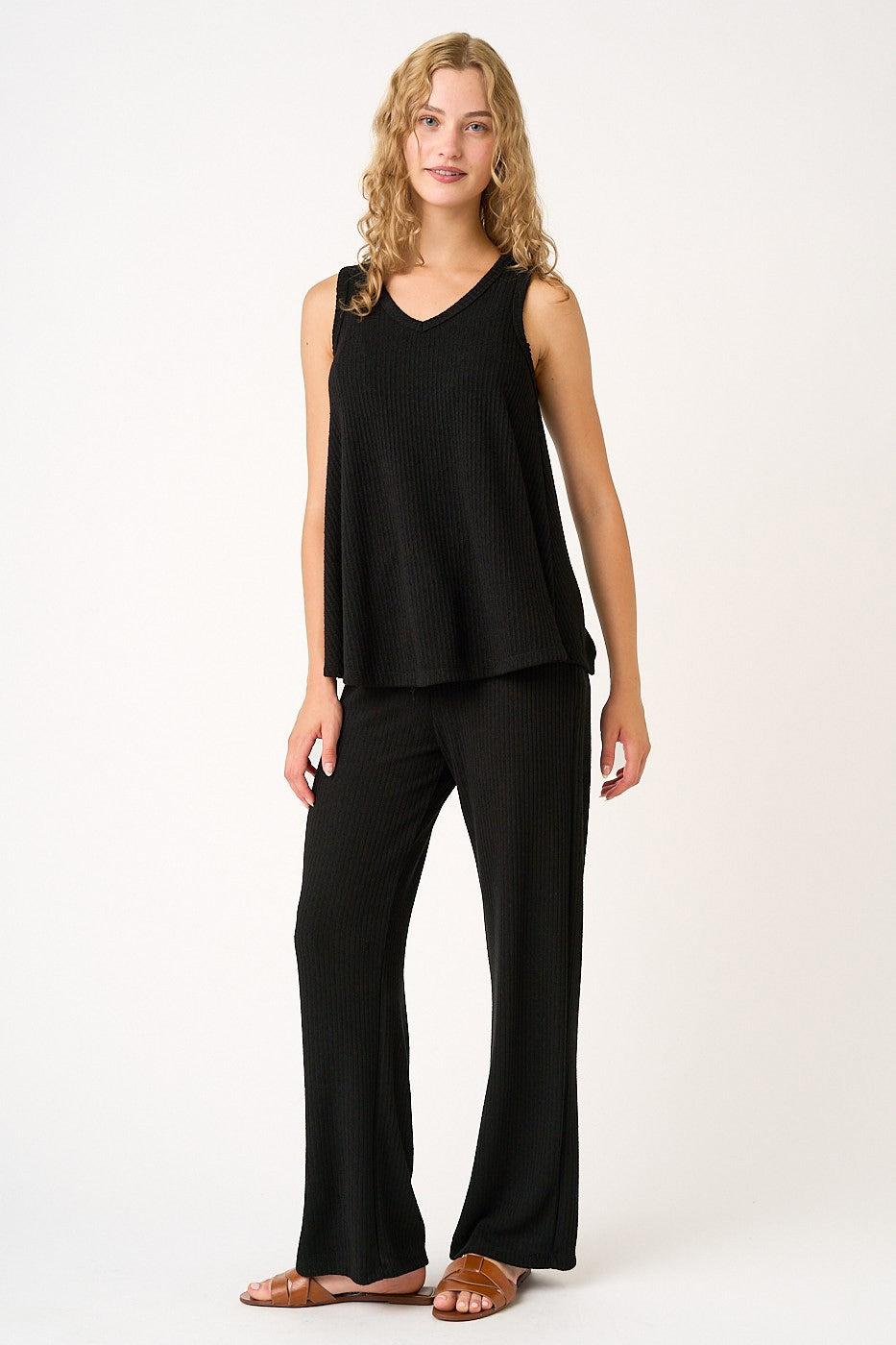 woman wearing a black ribbed sleeveless top and matching wide-leg pants, standing with a relaxed pose
