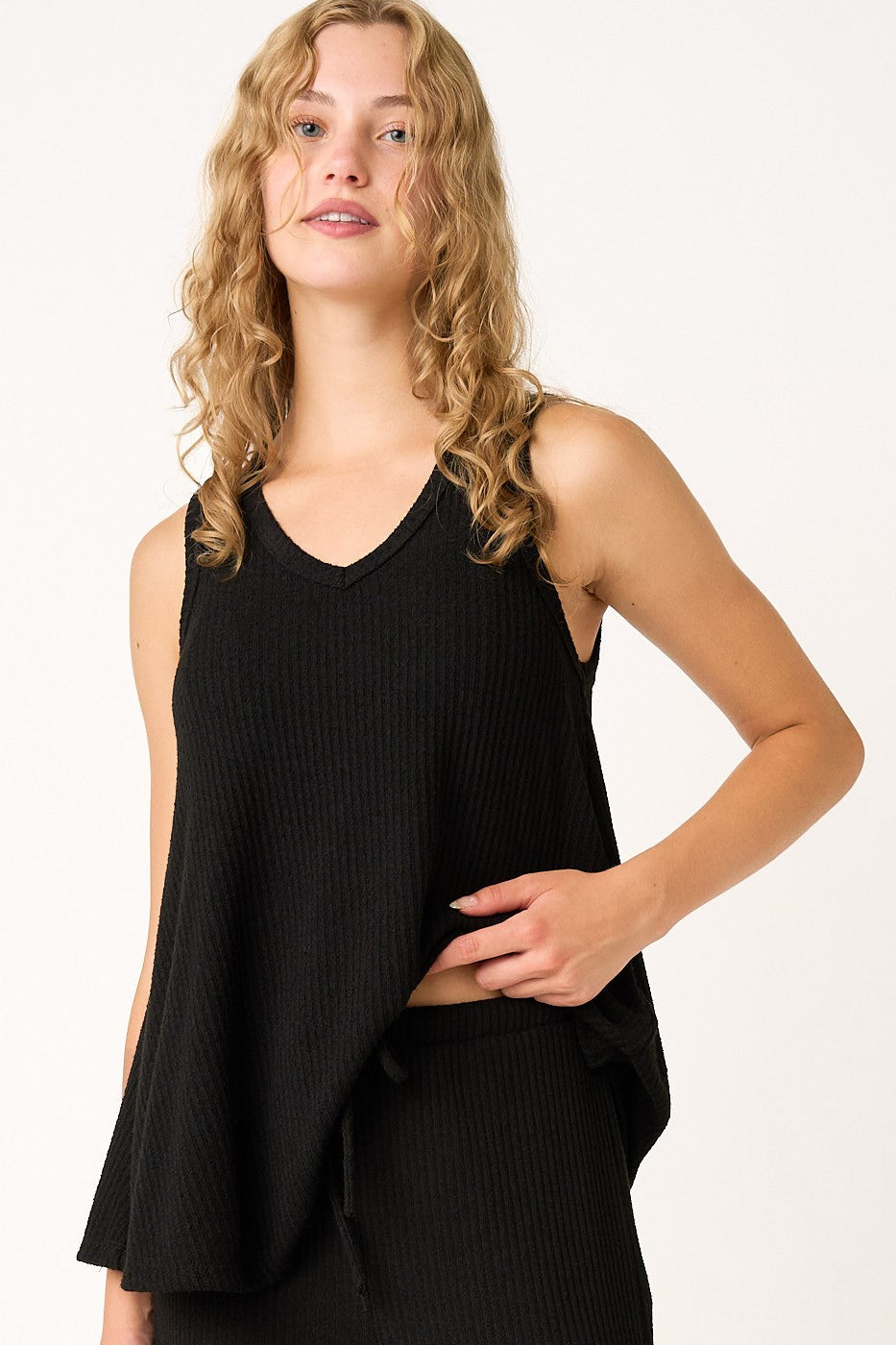 woman wearing a black ribbed sleeveless top with a v-neckline and a loose fit