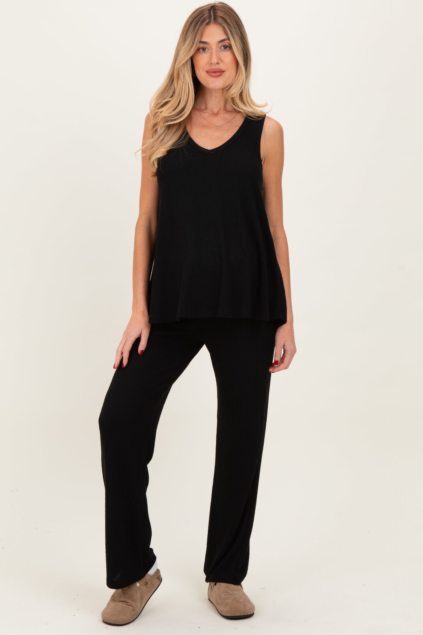 woman wearing a black maternity lounge set with a sleeveless top and matching pants, showcasing her baby bump