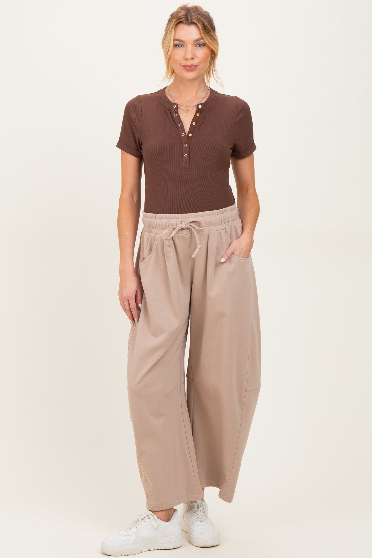 woman wearing a brown short sleeve henley top and light beige wide-leg maternity pants with pockets