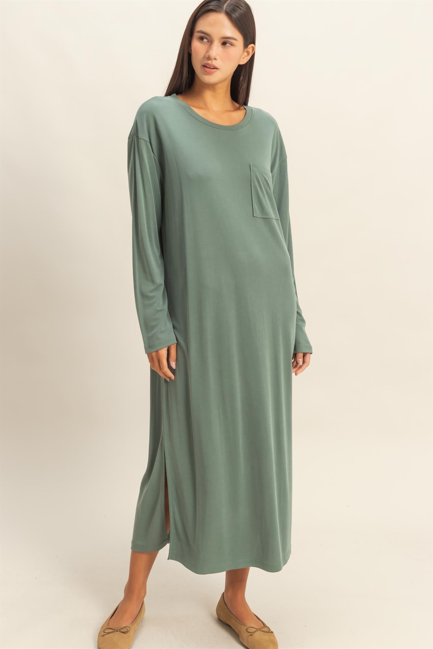 woman wearing a long sage green maxi dress with long sleeves and a side slit detail