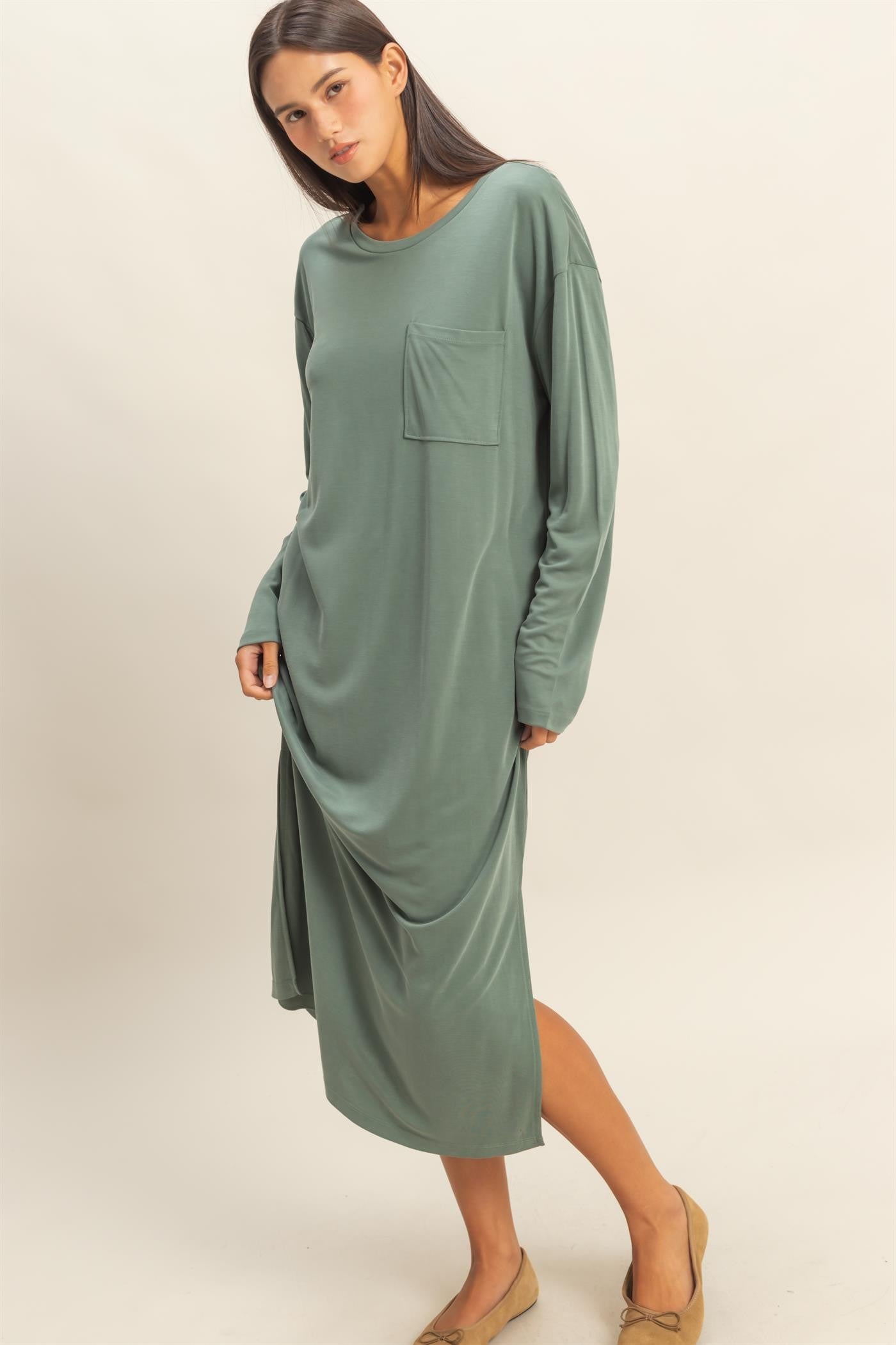 woman wearing a long sleeve sage green midi dress with a front pocket and relaxed fit