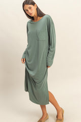 woman wearing a long sleeve sage green midi dress with a front pocket and relaxed fit