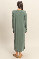 woman wearing a long green oversized dress with long sleeves and side slits, viewed from the back