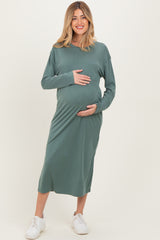 woman wearing a green long sleeve maternity dress and holding her baby bump