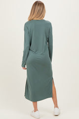 woman wearing a long sleeve green maternity dress with side slits, seen from the back