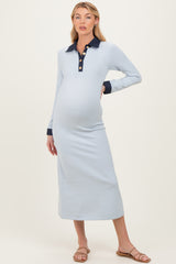 woman wearing a light blue long sleeve maternity dress with a navy collar and buttons, showing her baby bump