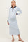 woman wearing a light blue long sleeve maternity dress with a navy collar and buttons, showing her baby bump