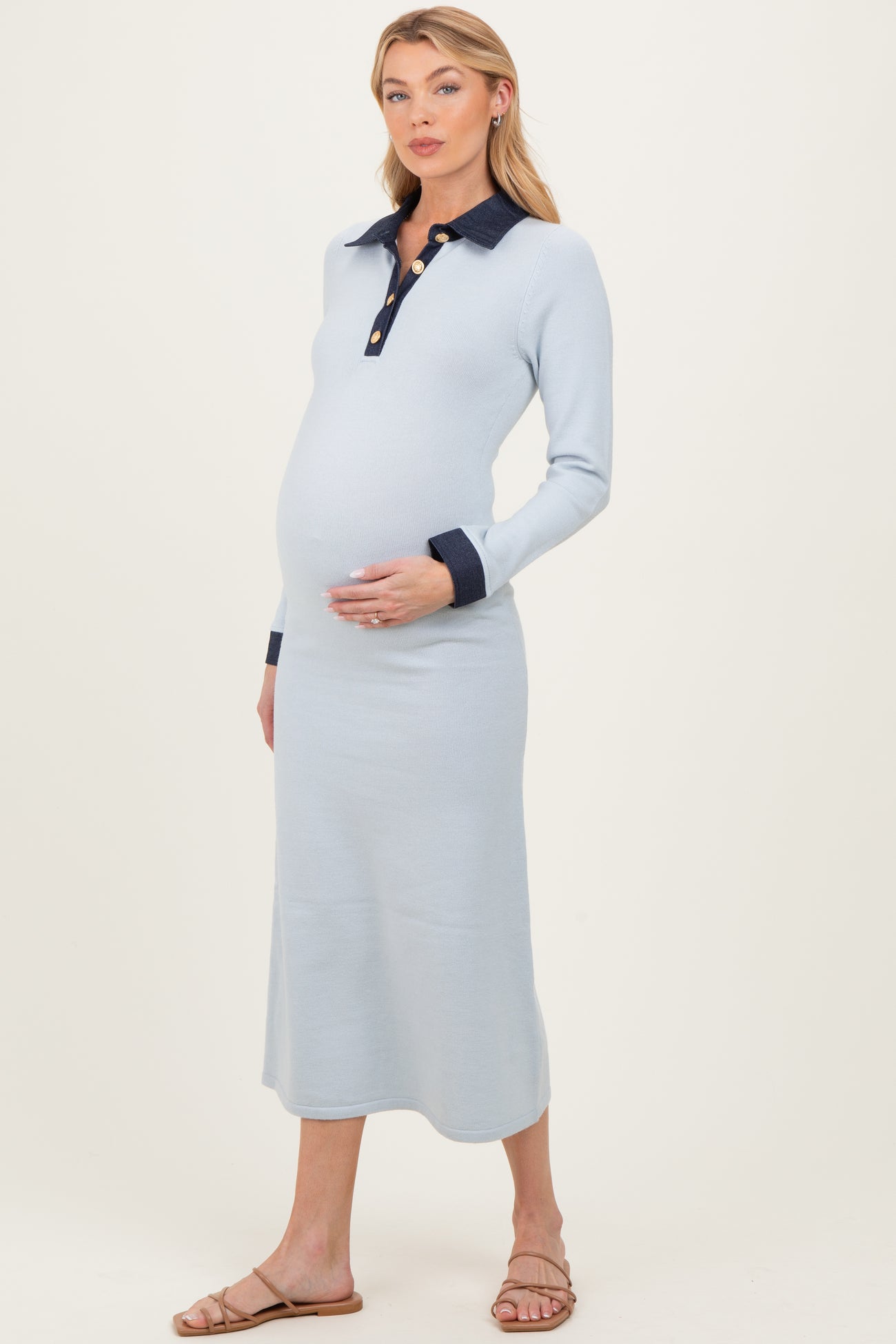 woman wearing a light blue maternity long sleeve polo dress, showcasing her baby bump with a navy collar and buttons
