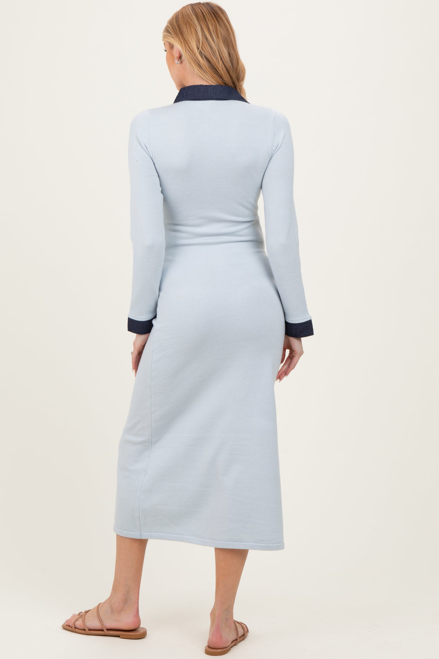 woman wearing a light blue long sleeve maternity dress with navy collar and cuffs, showing her back