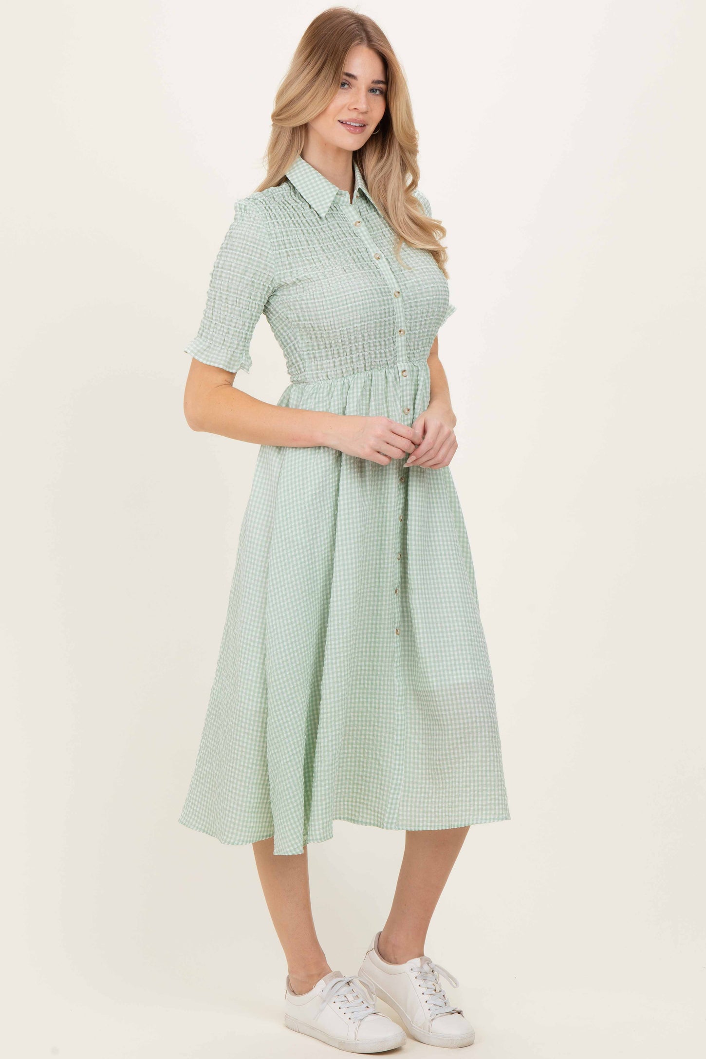 woman wearing a mint green gingham button-up midi dress with a fitted waist and short sleeves