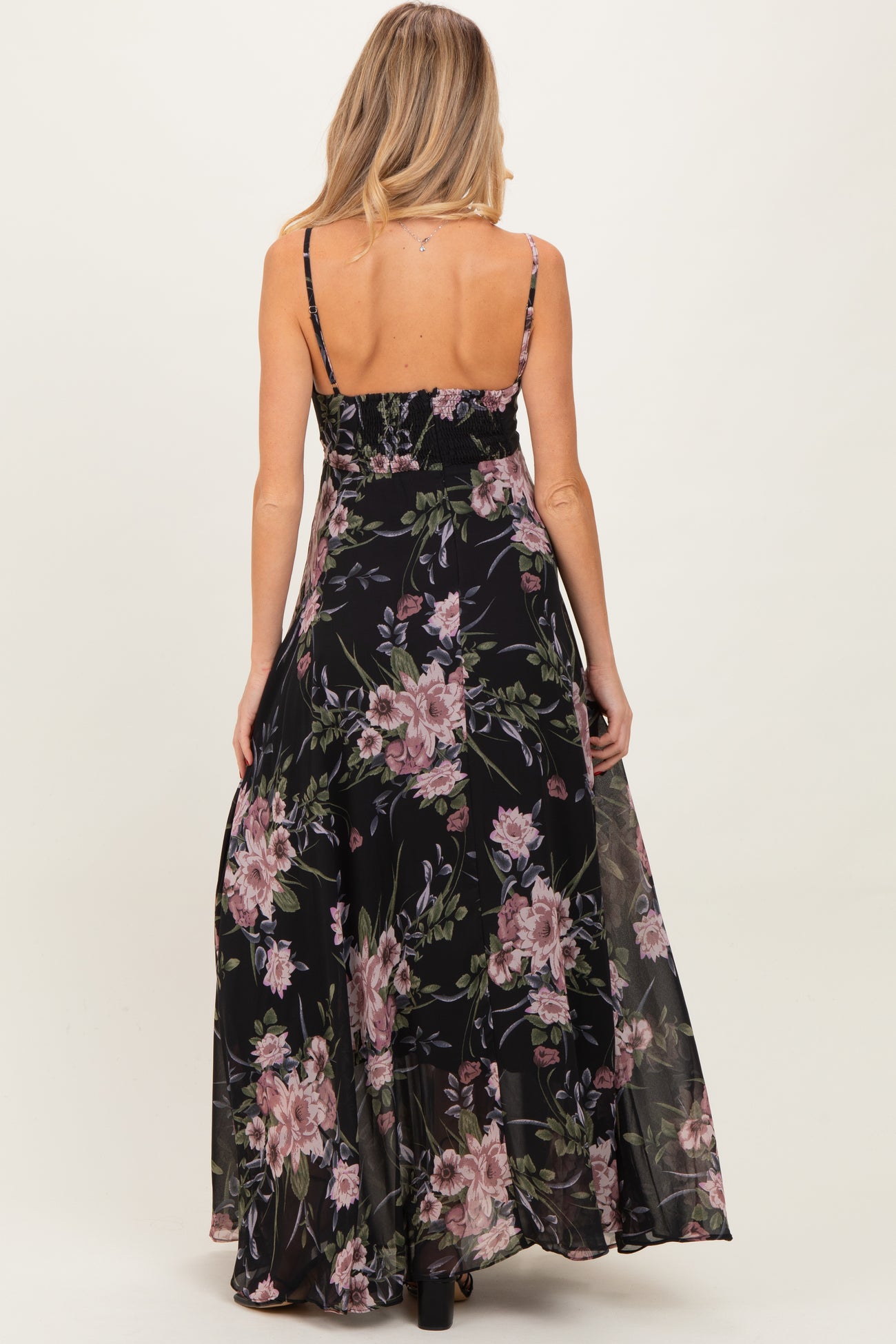 woman wearing a black floral maternity maxi dress, showing the back view with spaghetti straps