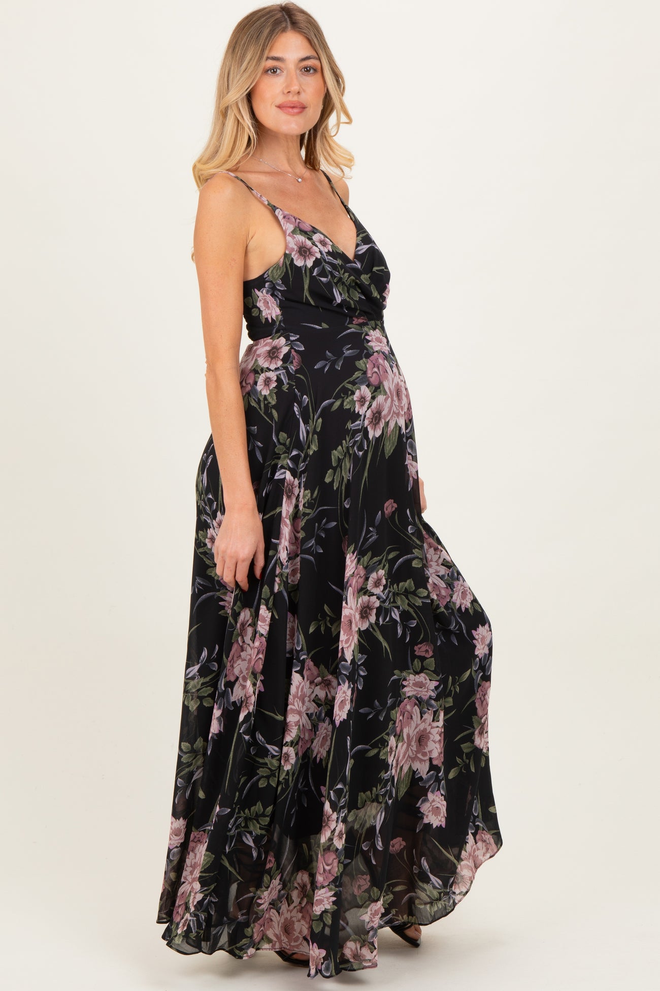 woman wearing a black floral maternity maxi dress with adjustable straps and a flowing skirt, showing her baby bump