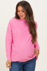woman wearing a pink maternity sweater with a relaxed fit and long sleeves, showing her baby bump