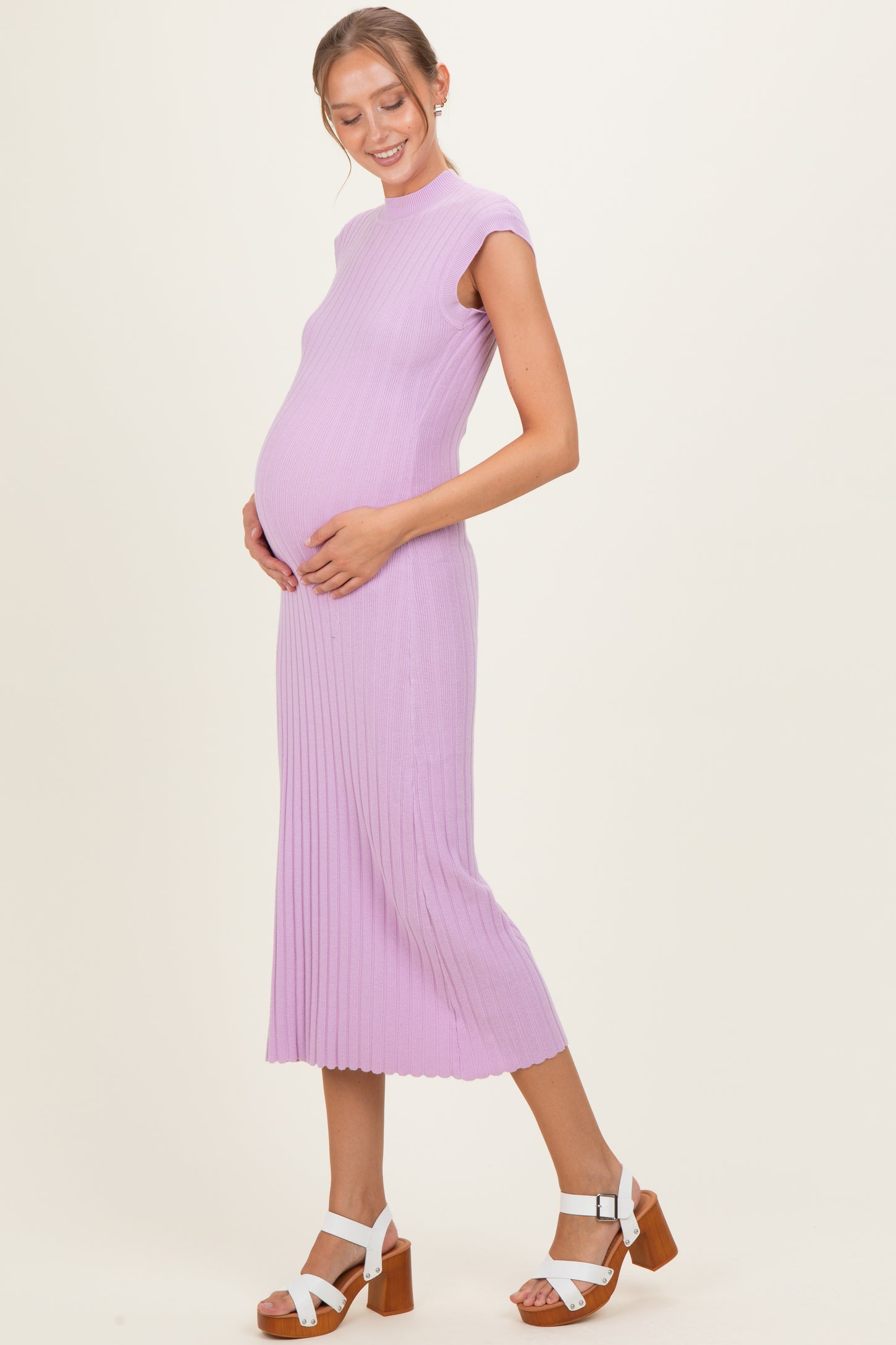 woman wearing a lavender ribbed maternity dress and holding her baby bump