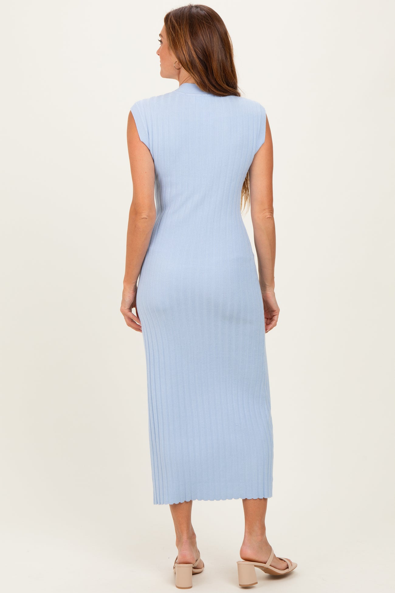 woman wearing a light blue sleeveless ribbed midi dress with a fitted silhouette and scalloped hem, viewed from the back