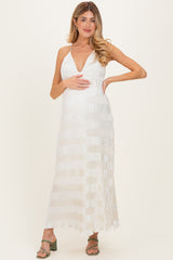 woman wearing a white pleated maternity dress and gently holding her baby bump