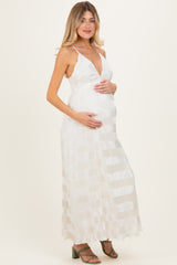 woman wearing a white striped maternity maxi dress and holding her baby bump