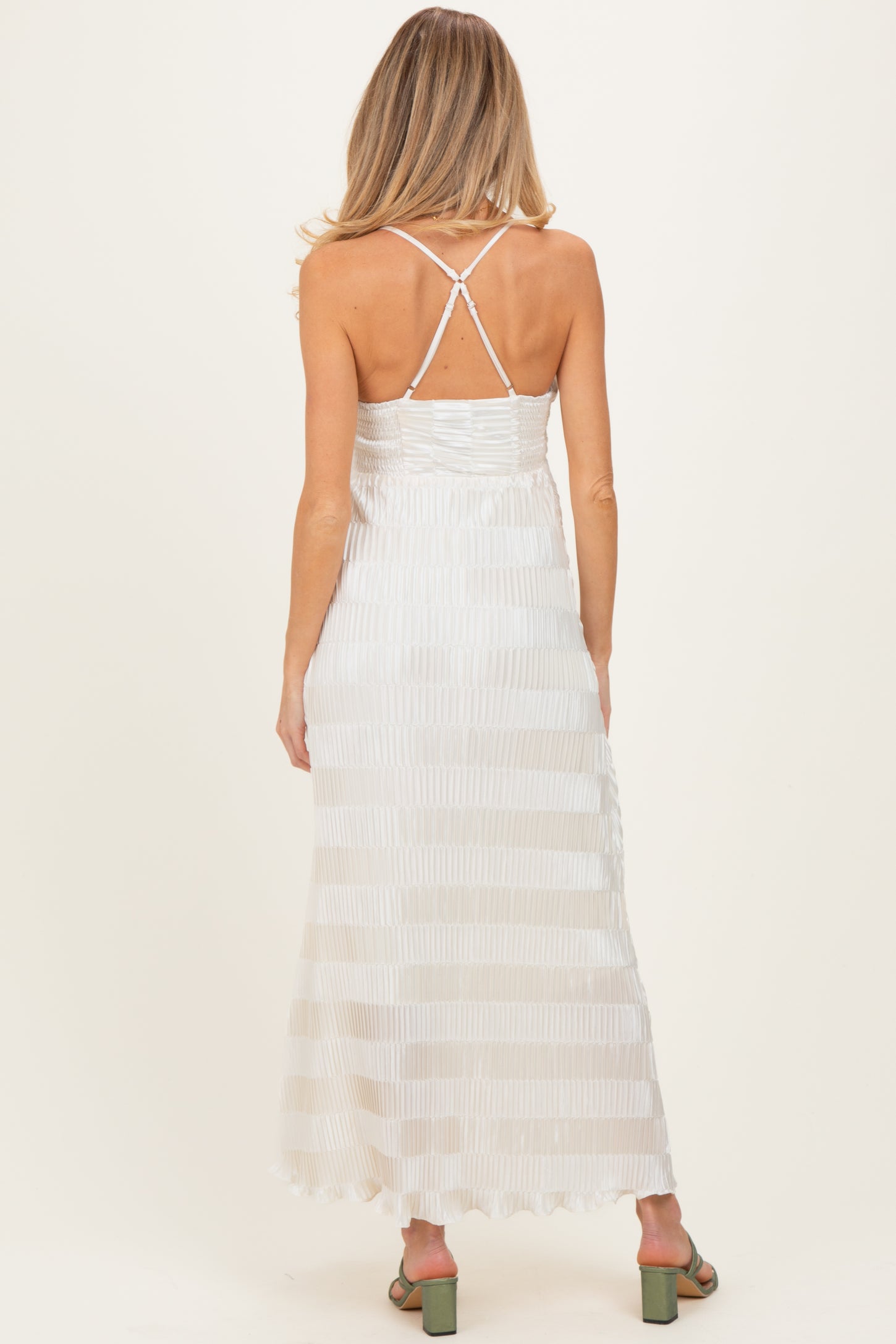 woman wearing a cream striped maternity maxi dress with a crisscross back and flowing fabric