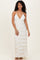 woman wearing a white striped maxi dress with a deep v-neck and thin straps, standing and smiling