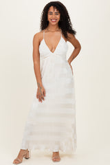 woman wearing a white striped maxi dress with a deep v-neck and halter straps