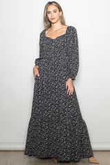 woman wearing a navy blue floral maxi dress with long sleeves and a square neckline, styled with a boho vibe